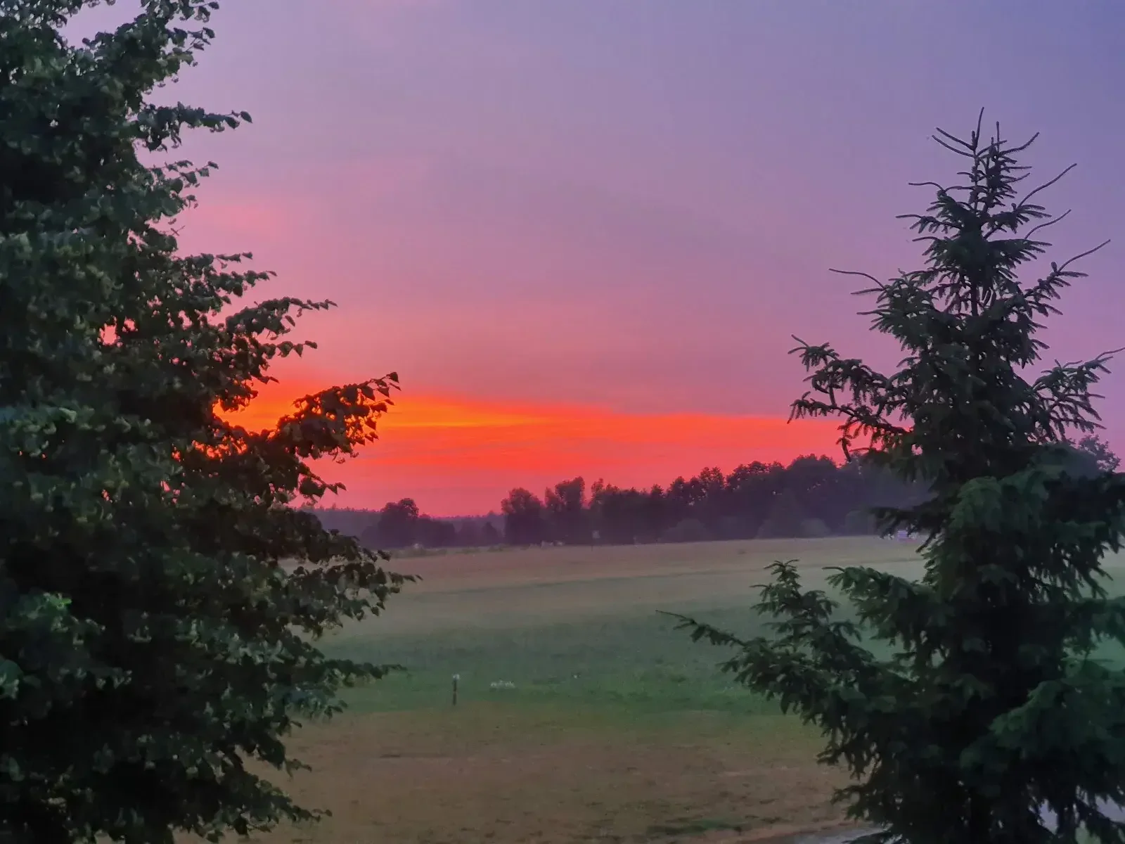 Płonące ognisko nocą nad jeziorem, ciepłe pomarańczowe światło na drewnie